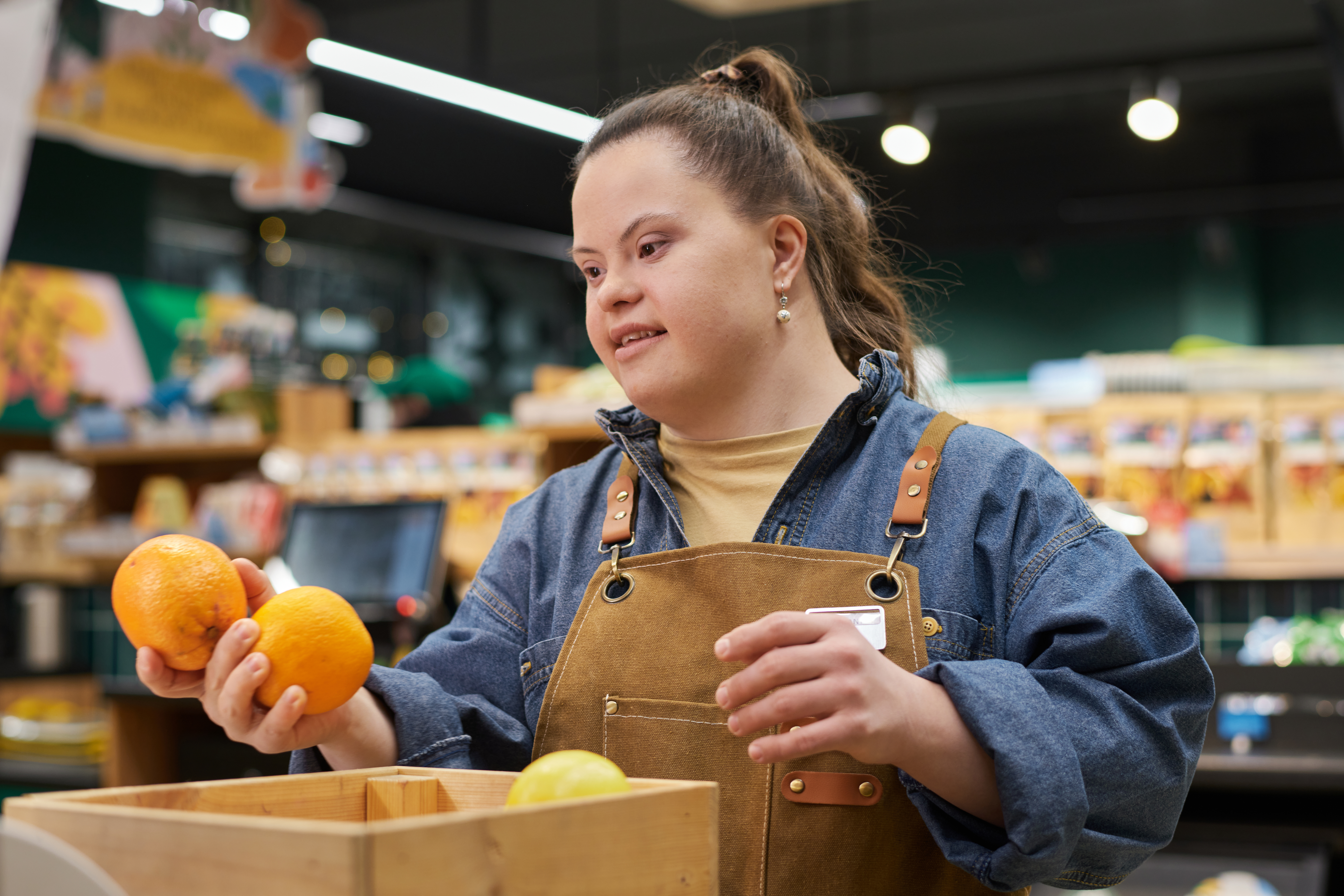 White woman with Downs Syndrome sorts fruit at her job at a grocery store.